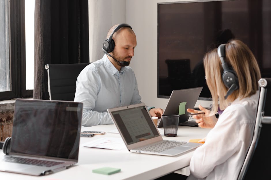 A group of diverse professionals collaborating in a modern office setting with laptops and technology.