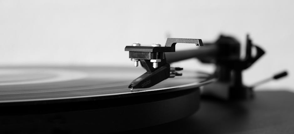 Black and white photo of a record player needle on a spinning vinyl, highlighting classic music technology.