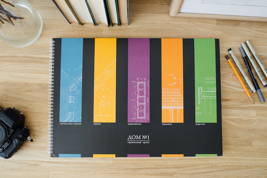 Design and architecture workbook with colorful blueprints on a wooden desk.