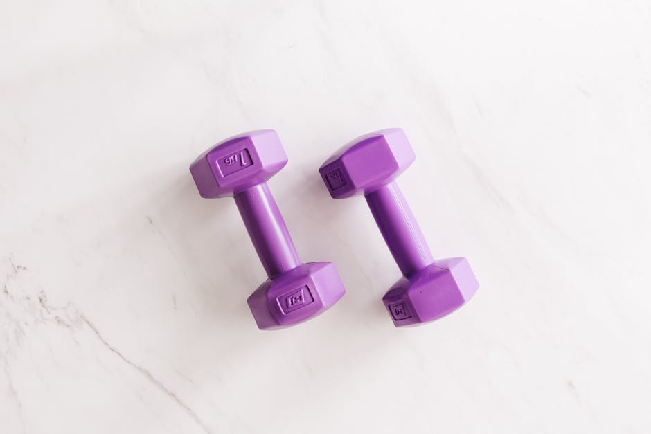 Overhead shot of two purple dumbbells on a white marble surface.