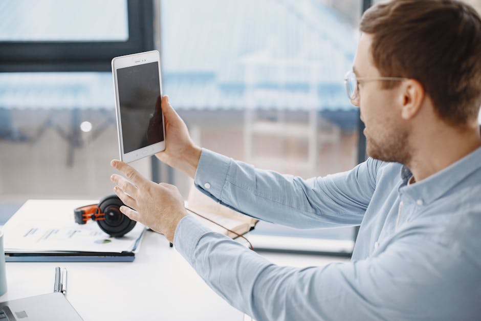 Businessman working remotely using a tablet in a modern office setting.