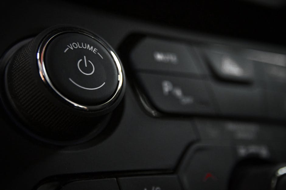 Detailed close-up of a vehicle's volume control knob and dashboard buttons indoors.