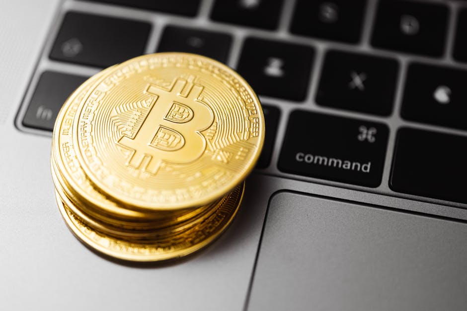 Close-up of gold bitcoin coins on a laptop keyboard, symbolizing digital currency and technology.