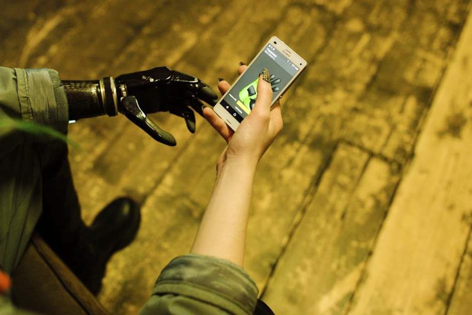 Person with prosthetic hand operating a smartphone, showcasing modern technology innovation.