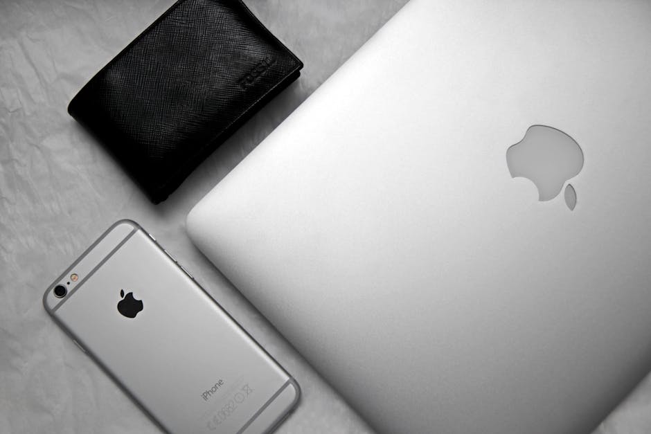 Flat lay of a sleek workspace featuring a smartphone, laptop, and wallet on a textured background.