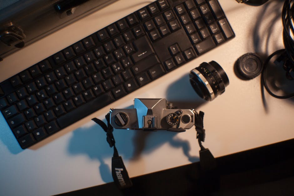 Overhead view of a vintage camera alongside a keyboard on a desk, creating a blend of technology and nostalgia.