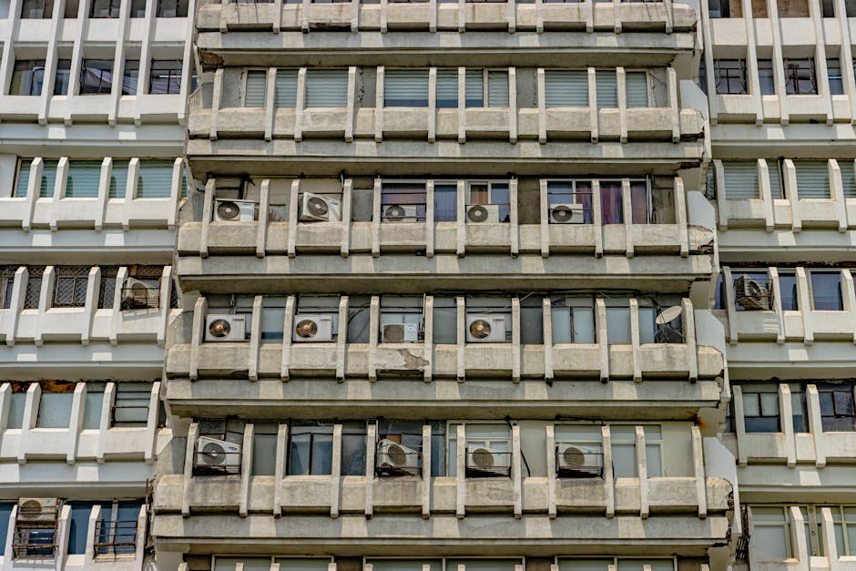 A detailed view of a brutalist building's symmetrical facade in New Delhi, featuring numerous air conditioning units.