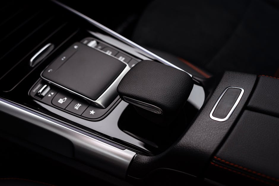 Close-up of a sleek luxury car's modern gear console, featuring leather and high-tech controls.