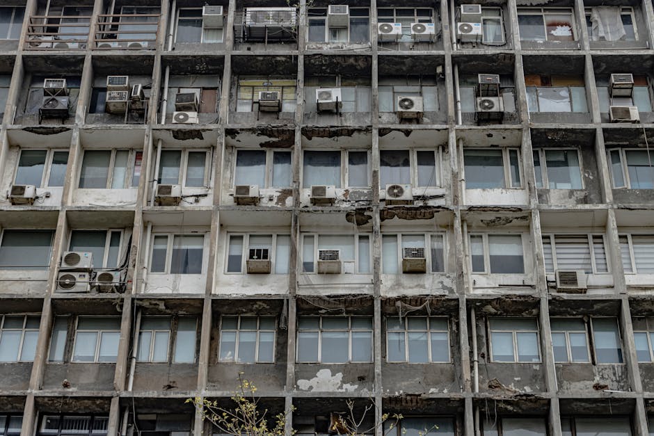 Close-up of a weathered apartment building with air conditioners, showcasing urban decay in New Delhi, India.
