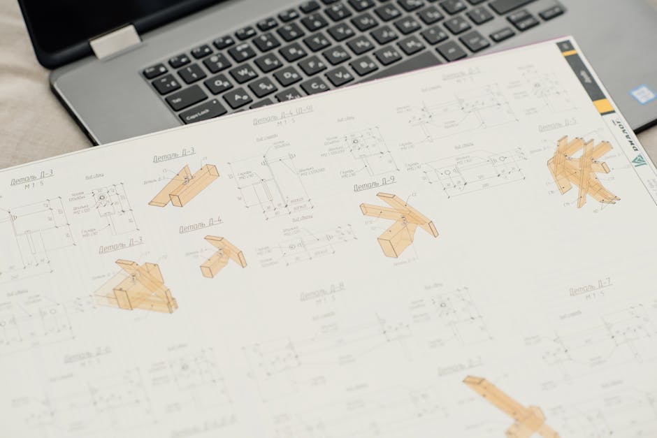 Close-up of architectural blueprints with a laptop on an office desk, showcasing design and planning.