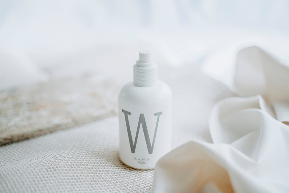 A close-up of a white cosmetic bottle with minimalist design on soft fabric background.
