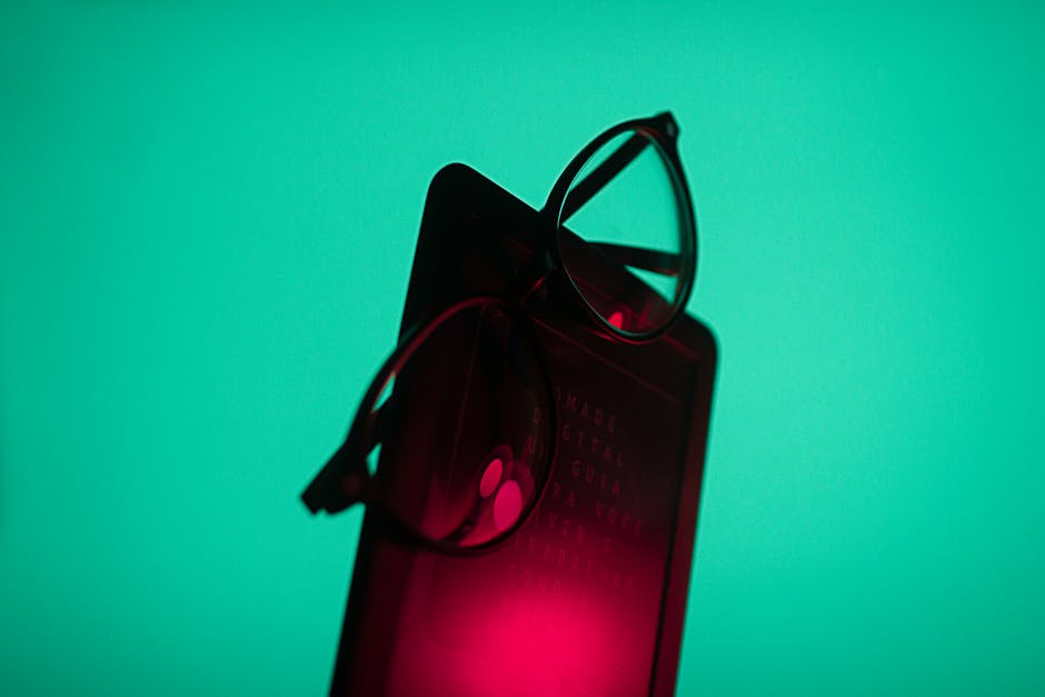 Stylish eyeglasses placed on a smartphone with a vibrant turquoise background.