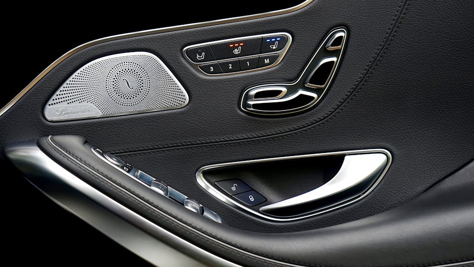 Close-up of a luxury car's interior door panel showcasing sleek design, buttons, and speaker.