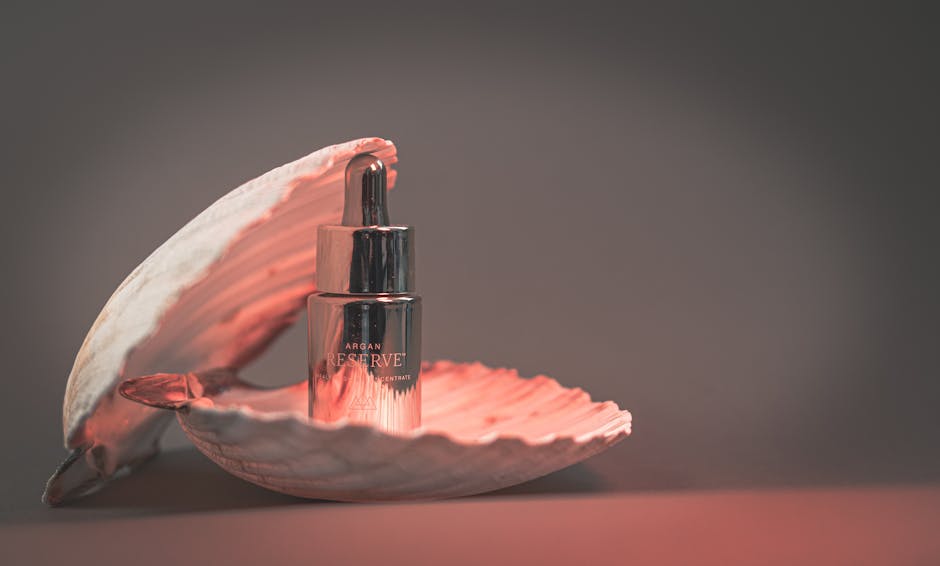 A stylish argan oil bottle elegantly placed inside an open seashell, set against a soft backdrop.