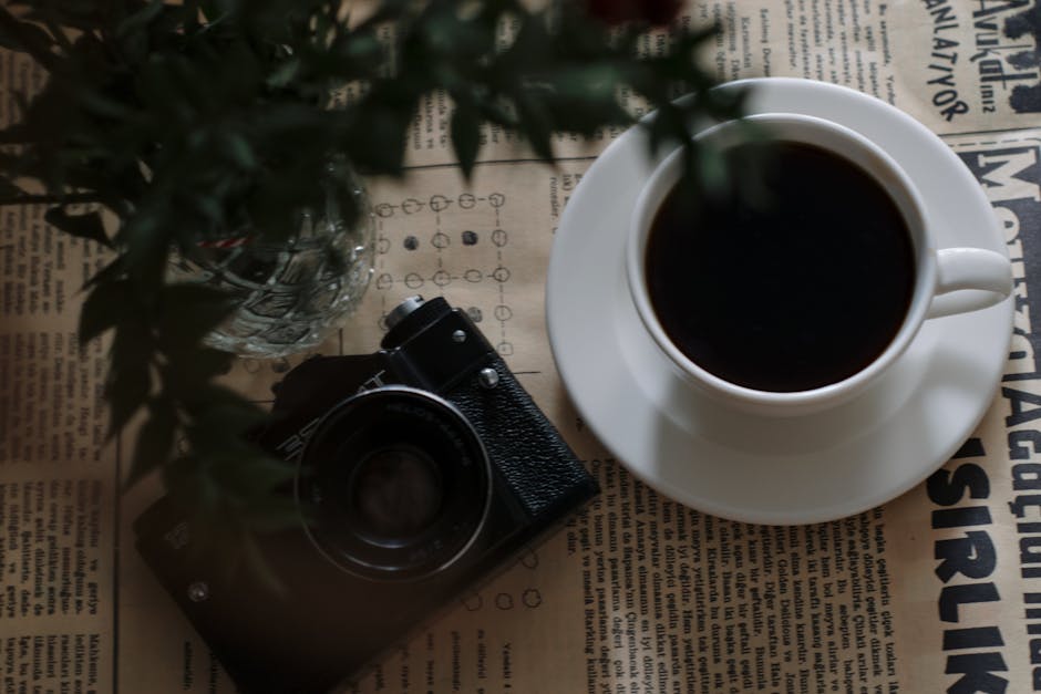 A cozy scene with a cup of coffee and a camera on a vintage newspaper setting.