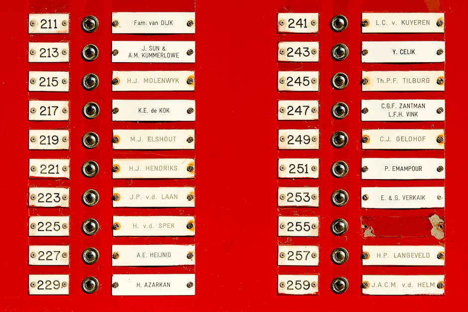 Close-up of a red doorbell panel with multiple nameplates and buttons in a building.