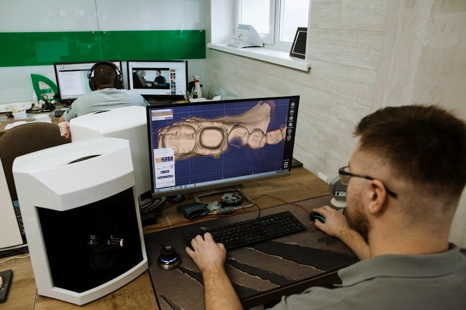 Dental technician using CAD software to design prosthetic teeth in a modern clinic.