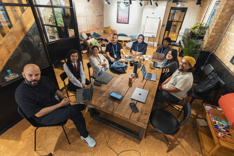 A group of diverse professionals collaborating in a modern office setting with laptops and technology.